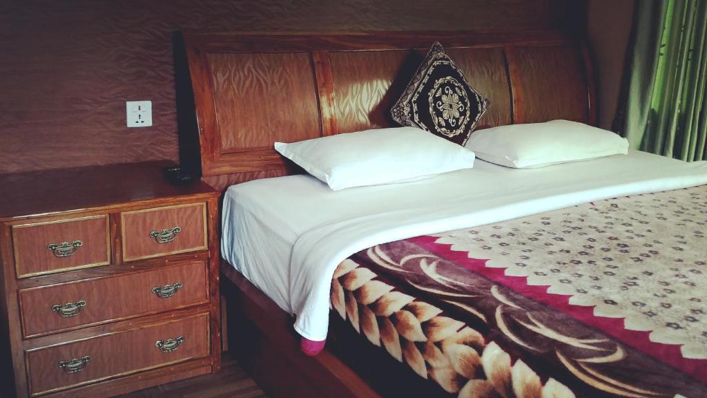 Bett mit einem Kopfteil aus Holz und einer Kommode in der Unterkunft Hotel Diplomat in Pokhara