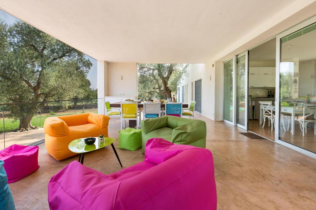 Salon na otwartym planie wyposażony jest w różowe i zielone meble. w obiekcie Villa Carlita by Perle di Puglia w mieście Specchiolla