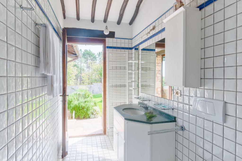 une salle de bain blanche avec un lavabo et une fenêtre dans l'établissement Casale Cipressi, à Castellina in Chianti