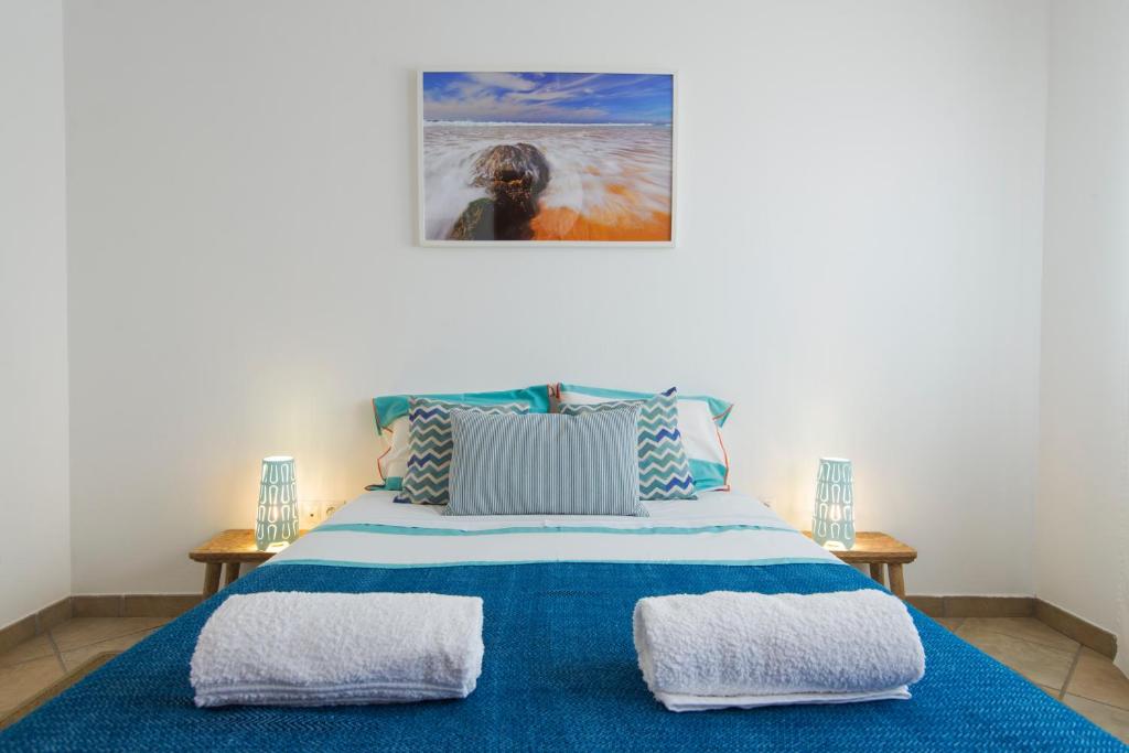 a bedroom with a blue bed with two pillows at By the C house in Vila Nova de Milfontes