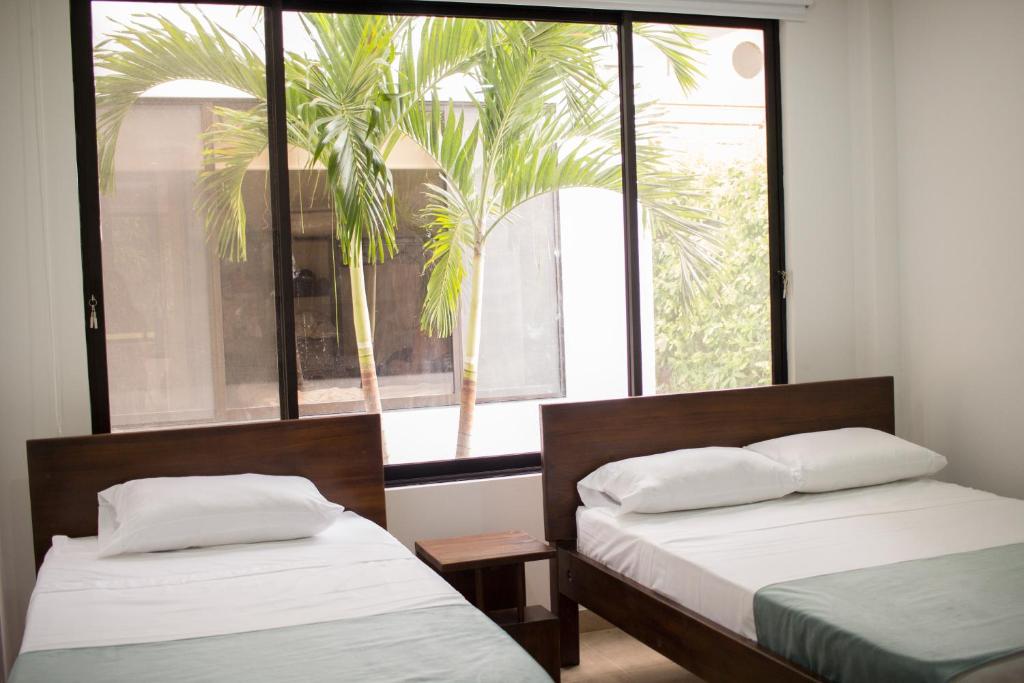 2 camas en una habitación con ventana y palmera en Villa Campestre Numbana Melgar, en Melgar