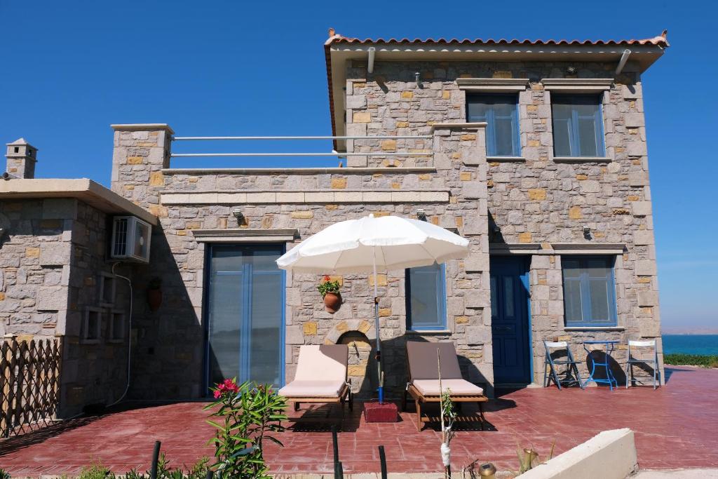 a house with two chairs and an umbrella at Fanaraki villas in Moudhros