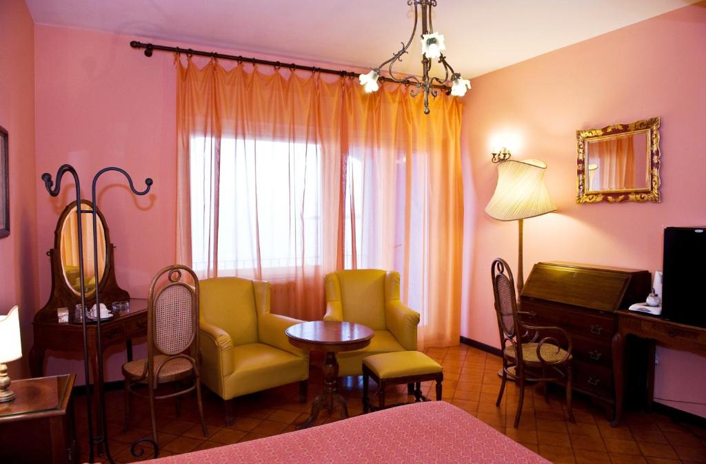 a room with a bed and chairs and a table at Hotel Palladio in Giardini Naxos
