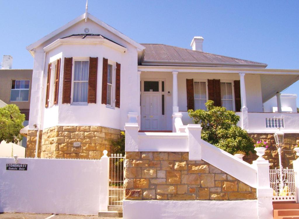 een huis met een wit hek ervoor bij Stonehurst Guest House in Kaapstad