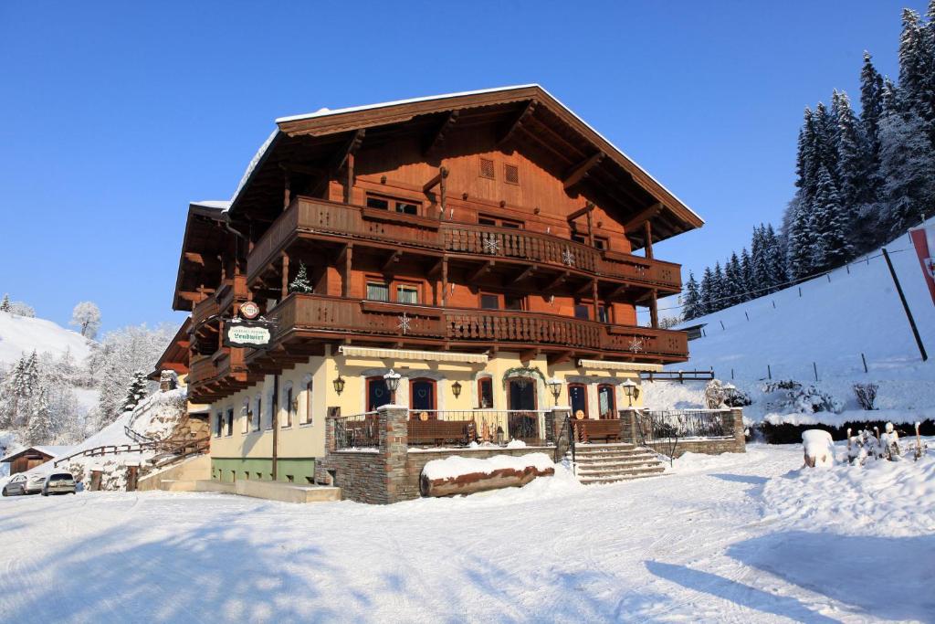 un gran edificio de madera en la nieve en Gasthof Zum Lendwirt, en Westendorf