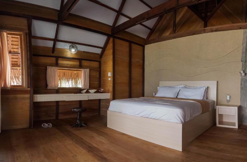 a bedroom with a bed and a desk at Kimo Resort Pulau Banyak Aceh Singkil in Alaban