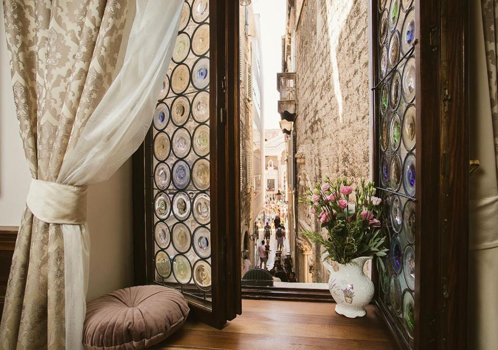 a room with a window with a vase of flowers next to a window at Heritage Hotel Cardo in Split