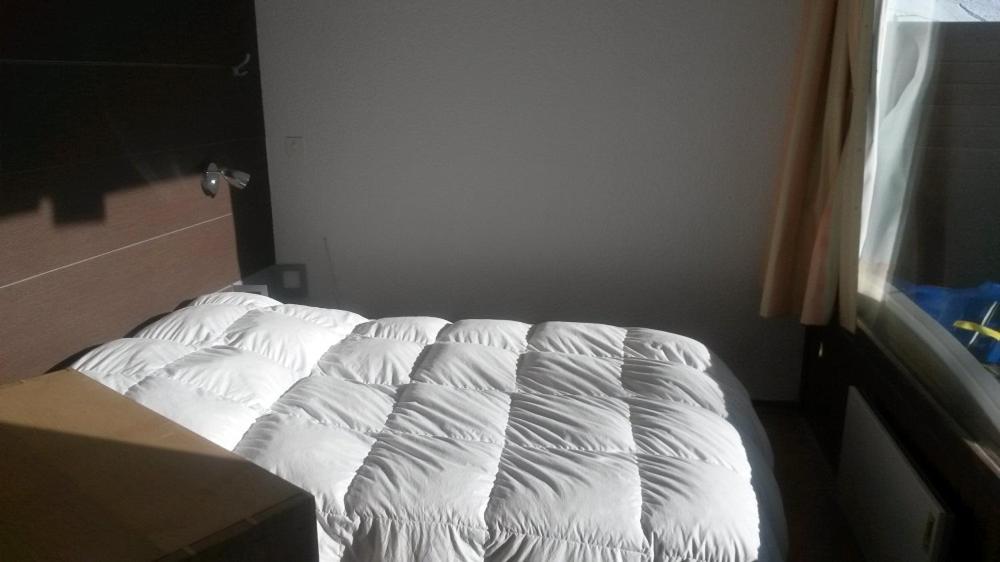 an unmade bed in a bedroom next to a window at Ski Soleil 108 in Manigod