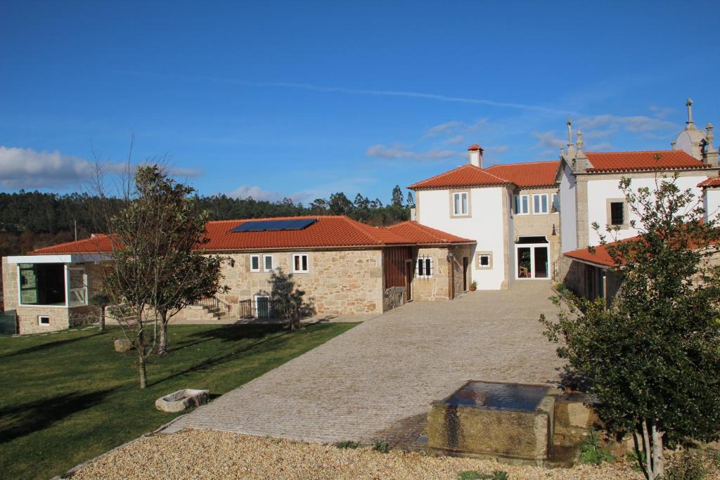 een groot wit huis met rode daken en een oprit bij Casa da Capela in Paredes de Coura