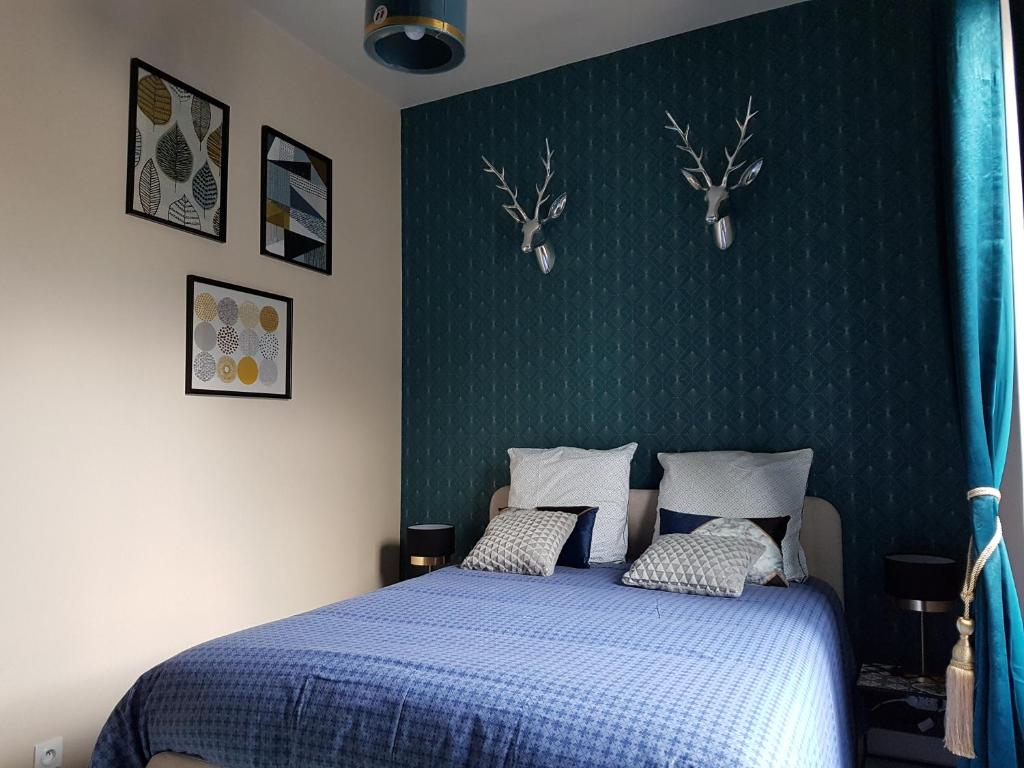a bedroom with a blue bed with deer heads on the wall at Le Prestige Saint André in Châteauroux