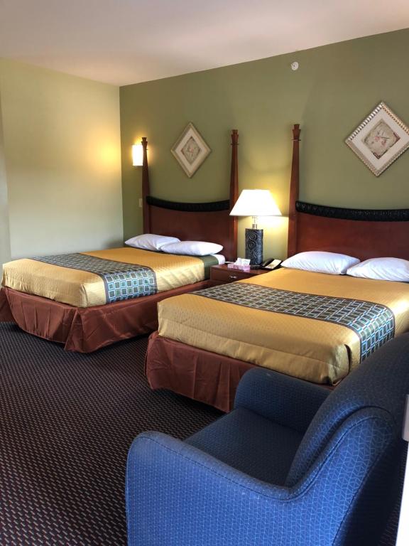 a hotel room with two beds and a chair at Budget Inn Williamsport in Williamsport