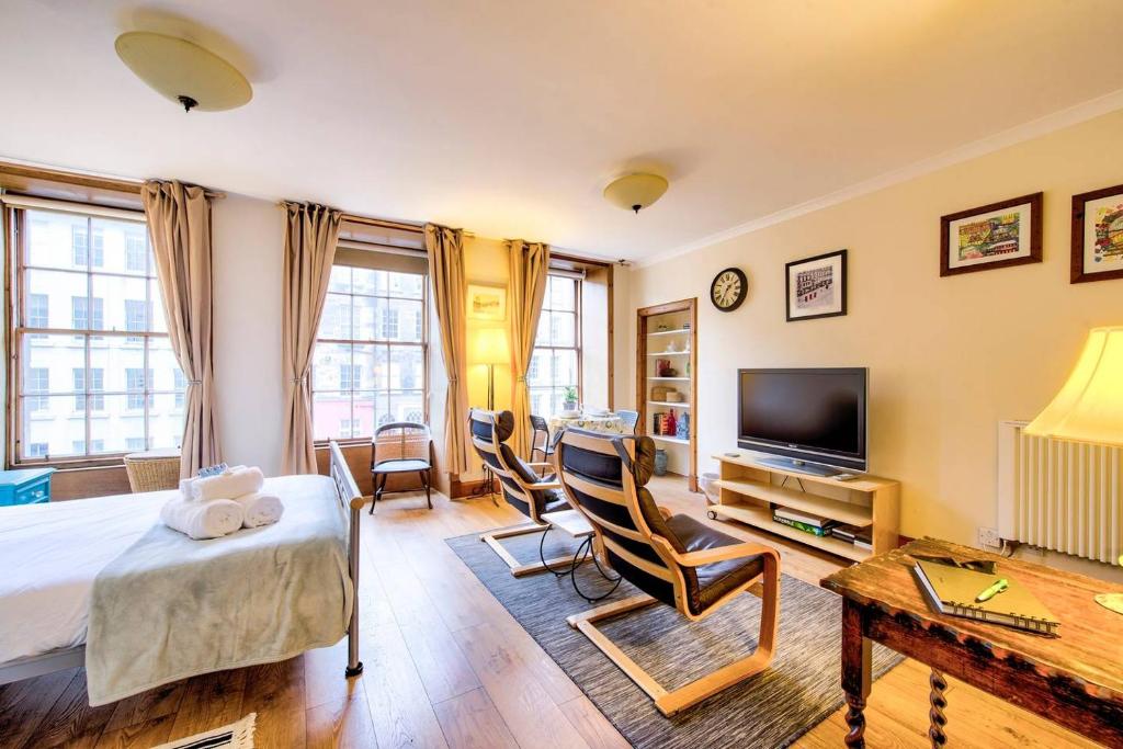 a bedroom with a bed and chairs and a television at ALTIDO Royal Mile Apartment for Two - Location, Location! in Edinburgh