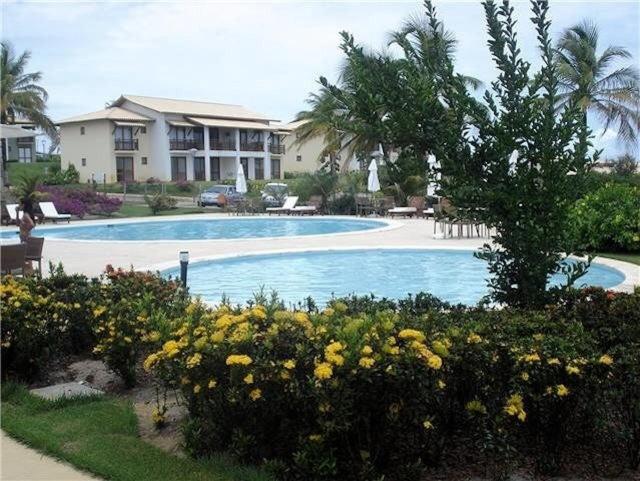 a large swimming pool in a resort with flowers at Condomínio Reserva Imbassai in Imbassai