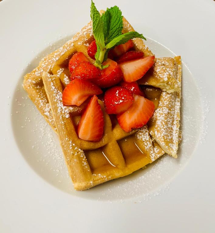 a plate of waffles with strawberries and powdered sugar at Wyndham Garden Ft Lauderdale Airport & Cruise Port in Dania Beach