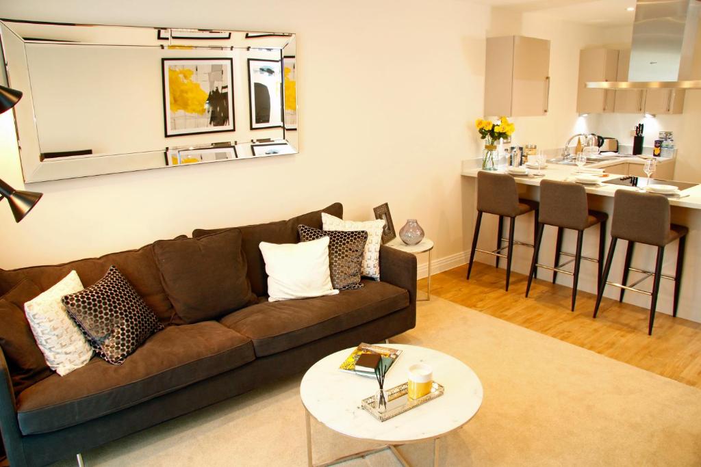 a living room with a couch and a kitchen at Portfolio Apartments - Welwyn Business Park in Welwyn Garden City