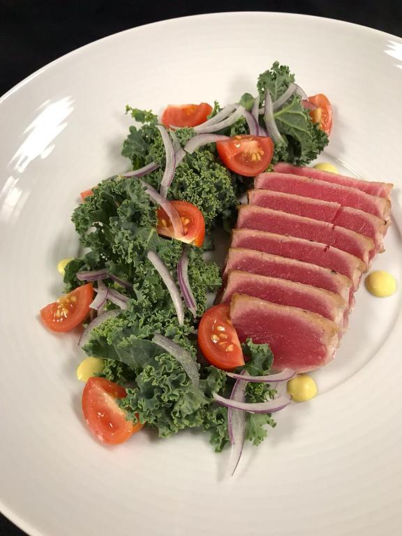 a white plate with a piece of meat and a salad at Wyndham Garden Ft Lauderdale Airport & Cruise Port in Dania Beach