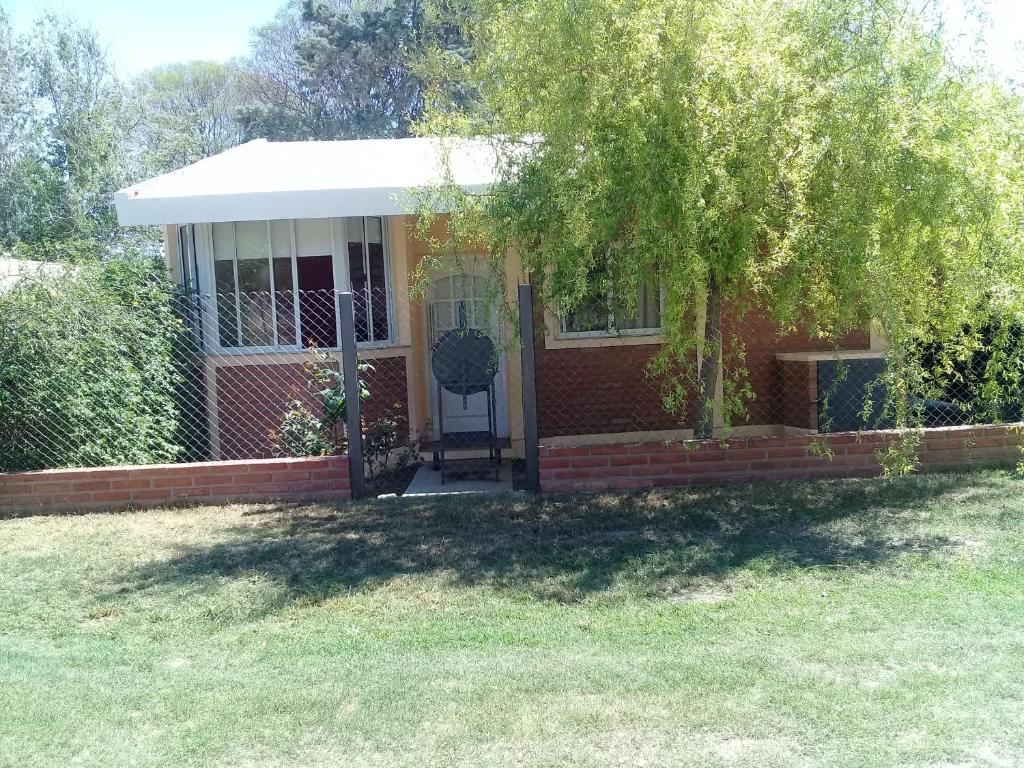 a small red brick house with a white porch at La casita de Chany in Mina Clavero