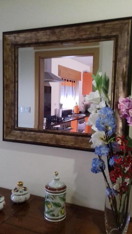 un espejo en una pared con un jarrón de flores en una mesa en Casa Da Fonte Da Torre, en Peso da Régua