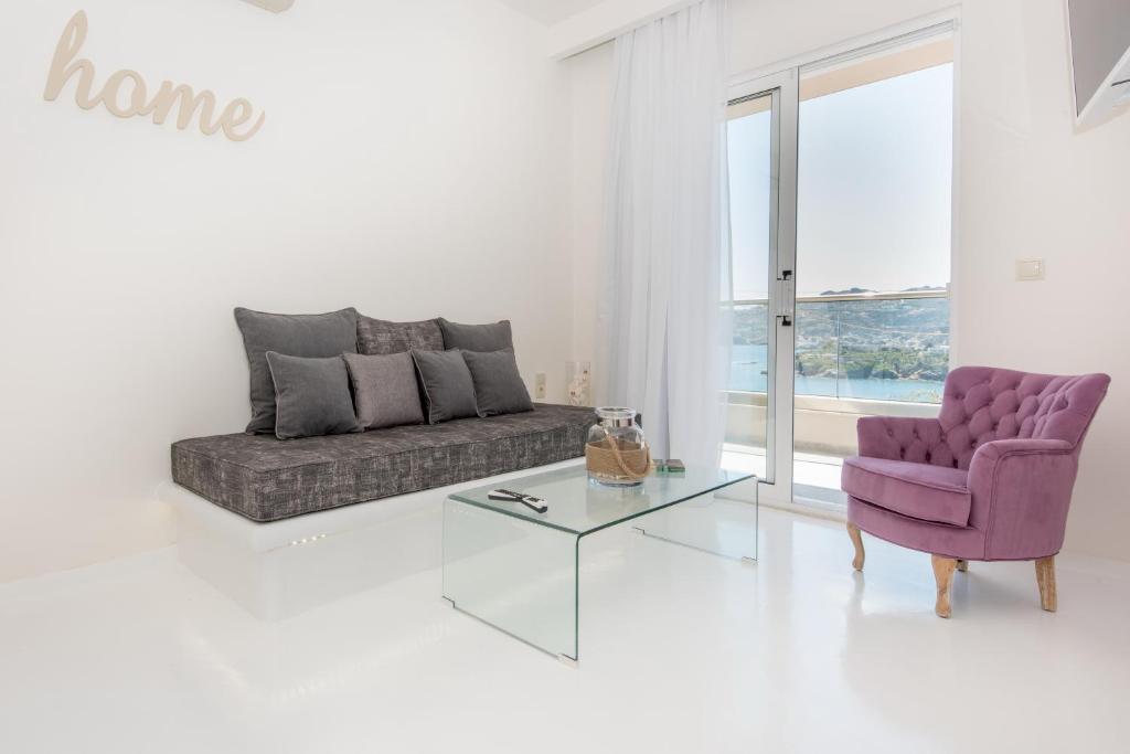 a living room with a purple couch and a glass table at Eva Mare Hotel & Suites - Adults only in Agia Pelagia