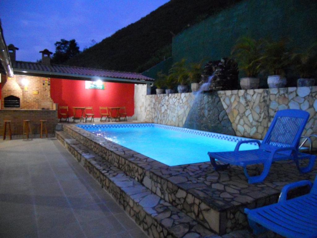 a swimming pool with a blue chair next to a house at Pousada O Meu Canto in Santa Rita de Jacutinga