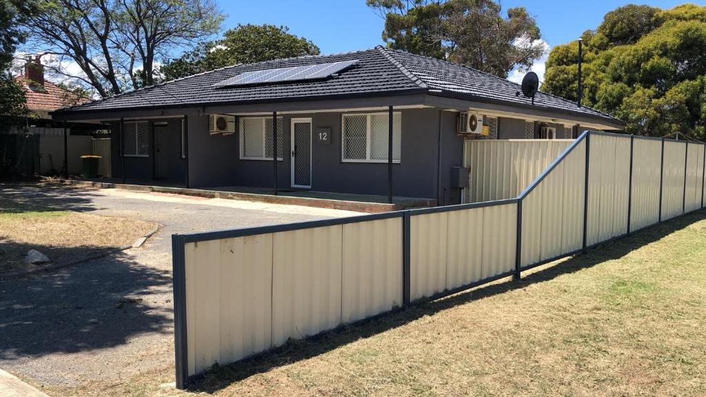una casa con una recinzione bianca davanti di Maddington House Unit A a Perth
