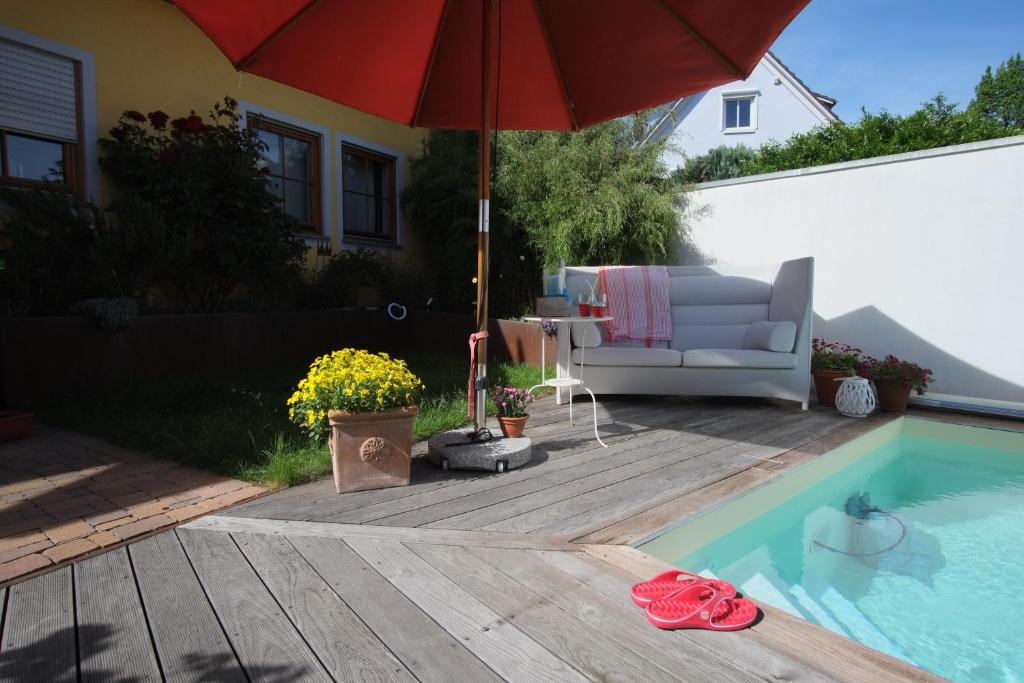 a patio with a chair and an umbrella next to a pool at Studio in der alten Scheune in Eschbach