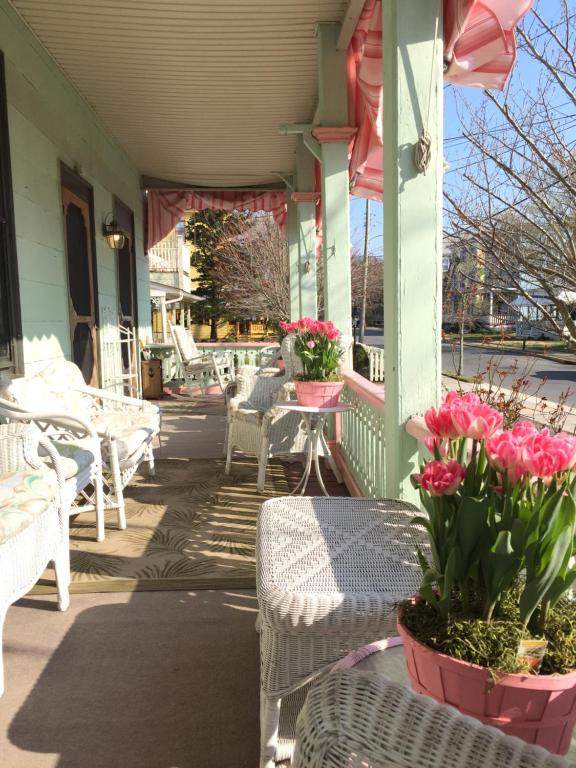 a porch with tables and chairs and pink flowers at First floor, 2 bedrm 2 bath, sleeps 6, Parking available, walk to Beach & Shop in Cape May