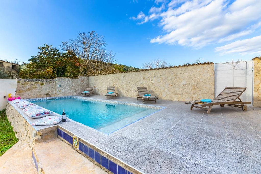 einen Pool mit 2 Stühlen und einem Tisch in der Unterkunft Villa Tipica Casa Tua in Ragusa