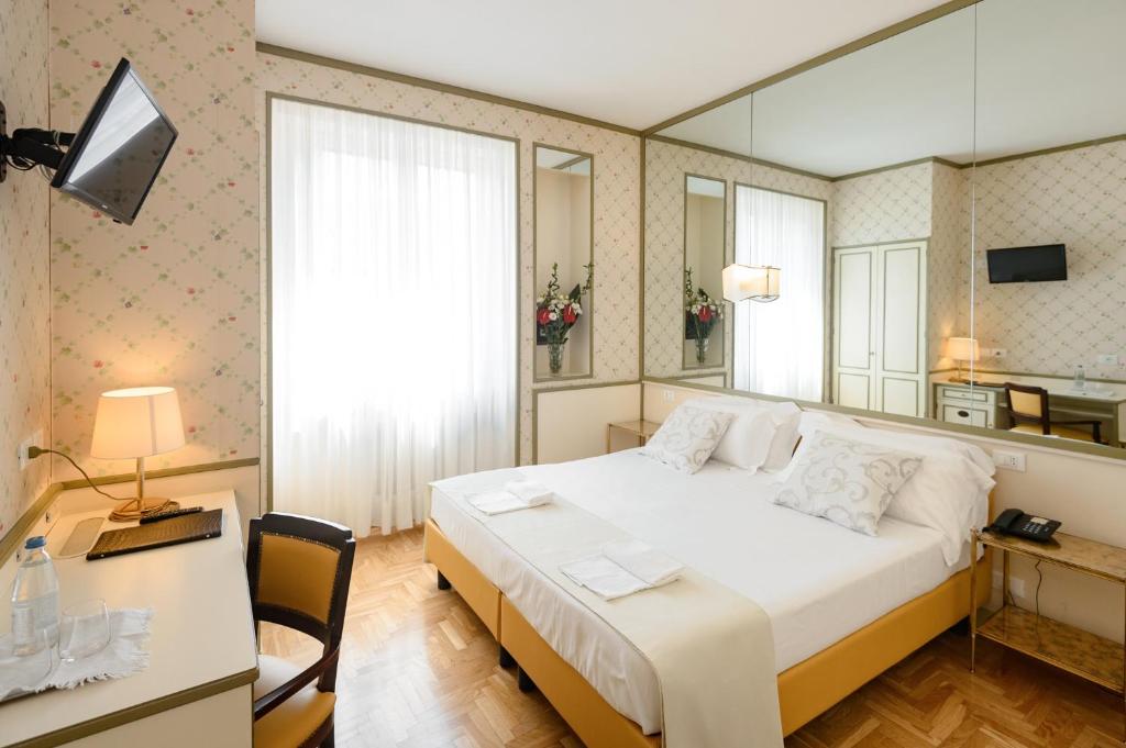 una camera con letto, scrivania e specchio di Hotel Continental a Treviso