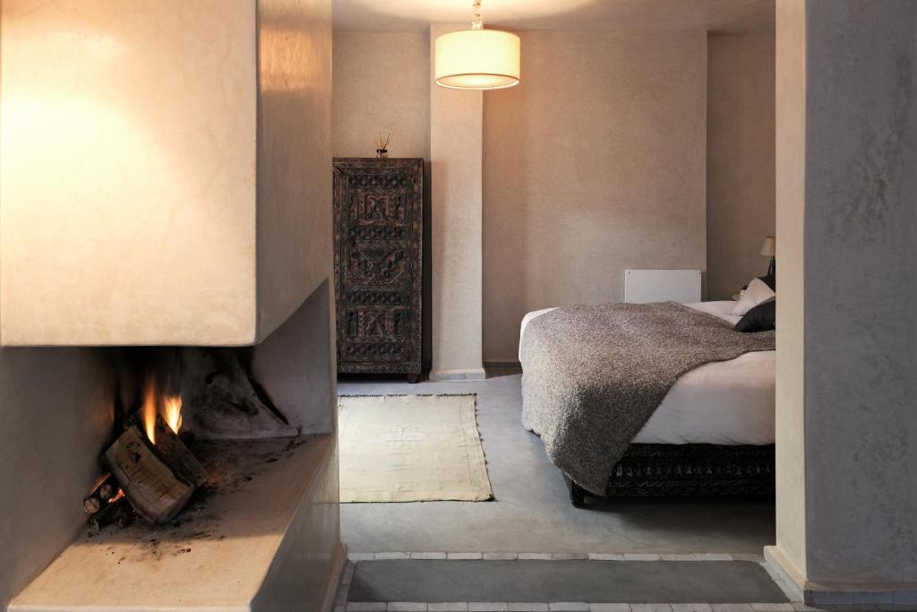 1 dormitorio con 1 cama y chimenea en Dar Les Sirènes, en Essaouira