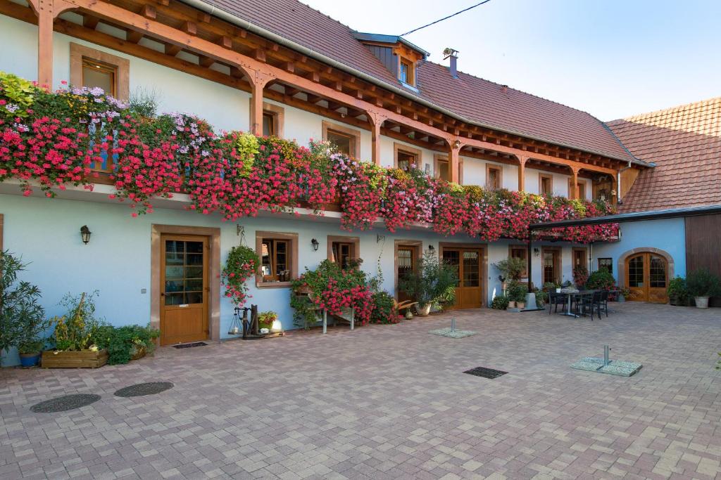 un edificio con flores a un lado. en La Ferme de Louise, en Hohengoeft