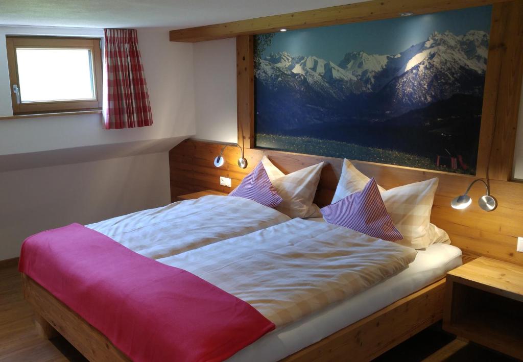 a bedroom with a large bed with a painting on the wall at Landhaus Alpenhof in Fischen