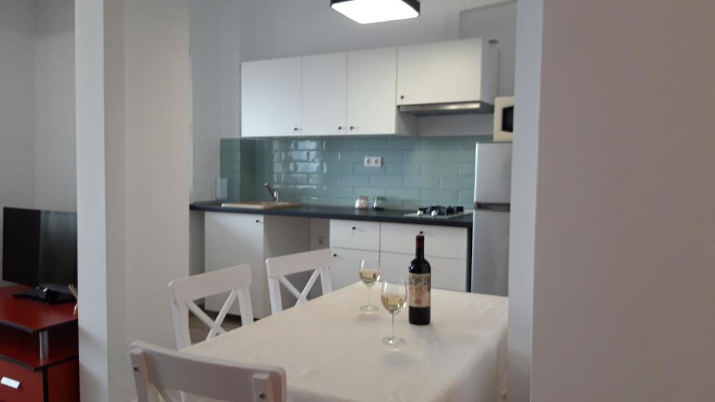 a white kitchen with a table with two glasses of wine at Cluj Accommodation Nasaud in Cluj-Napoca