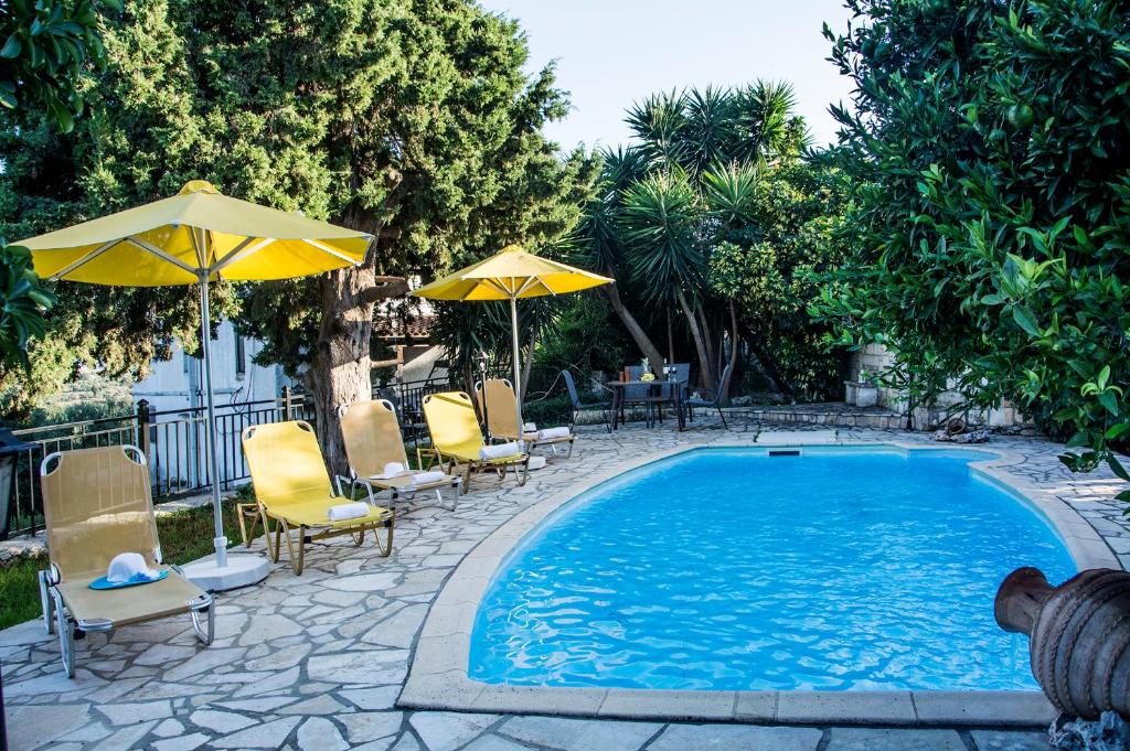 einen Pool mit Stühlen, Sonnenschirmen und einem Tisch in der Unterkunft Villa Dimitris in Kalamitsi Amygdali