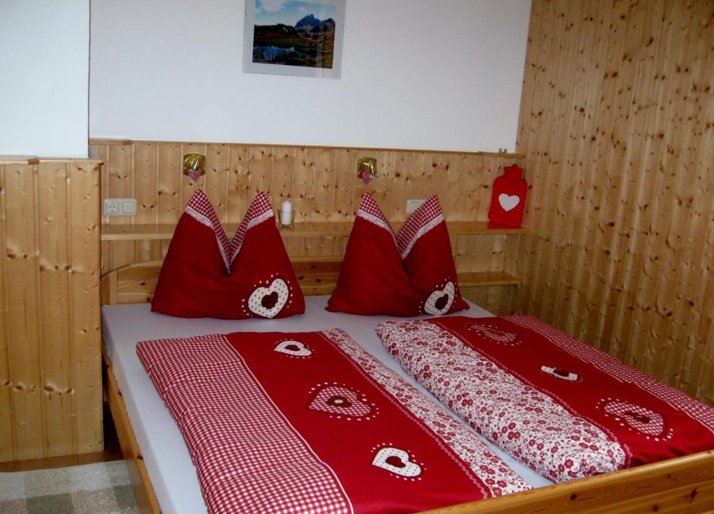 a bedroom with a bed with red and white pillows at Haus Klinger in Gaschurn