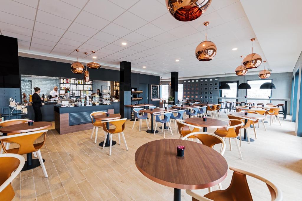 ein Restaurant mit Tischen und Stühlen und eine Bar in der Unterkunft B&B HOTEL Zürich Airport in Rümlang