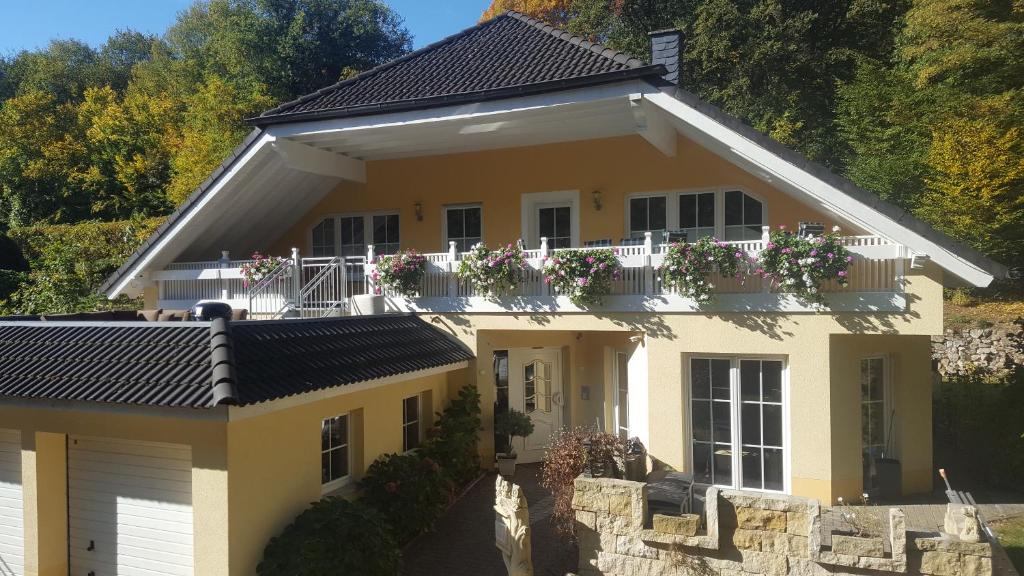 una casa amarilla con un balcón con flores. en Im Corveyer Wäldchen en Traben-Trarbach