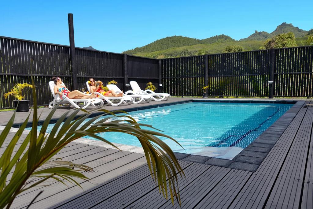 a group of people sitting in lawn chairs by a pool at Boaza Place in Arorangi