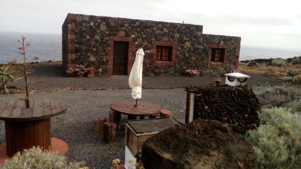 a stone building with a table and an umbrella at casa La Perdiz in Valverde