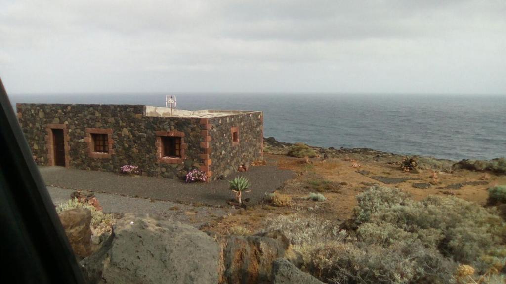 a stone building on the side of the ocean at casa La Perdiz in Valverde