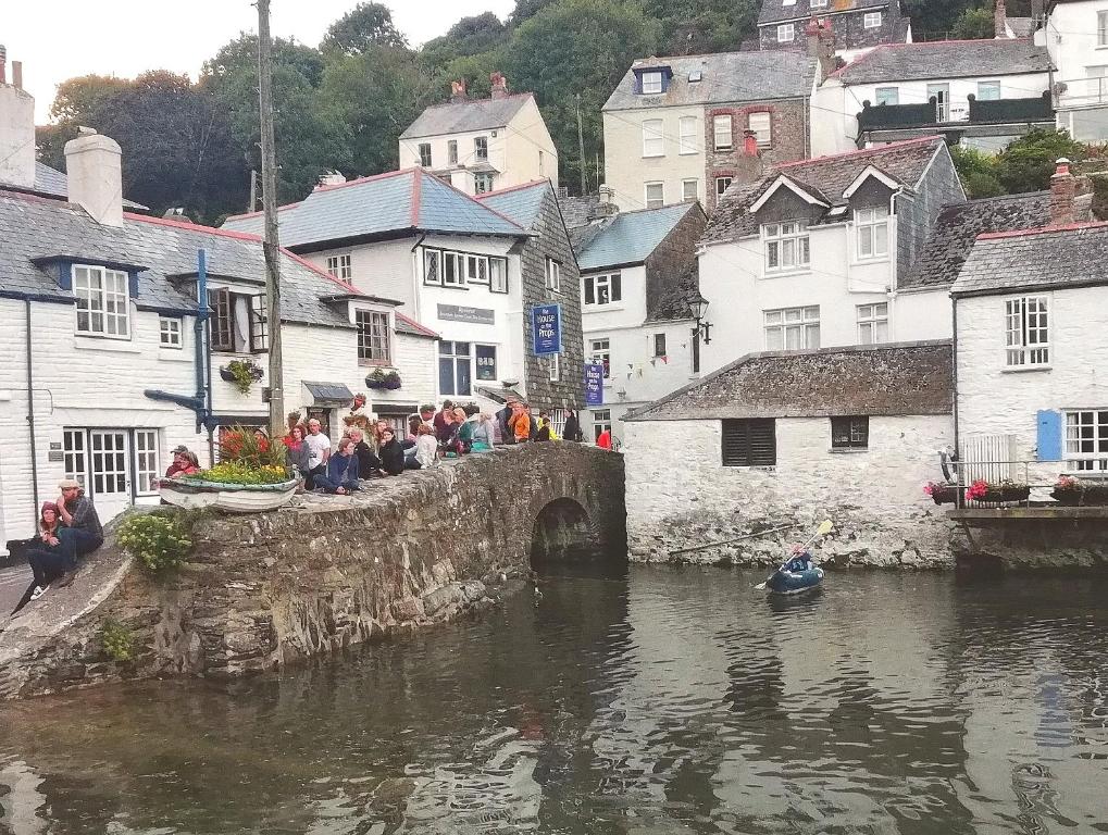 a group of people sitting on a bridge over a river at The House on the Props in Polperro