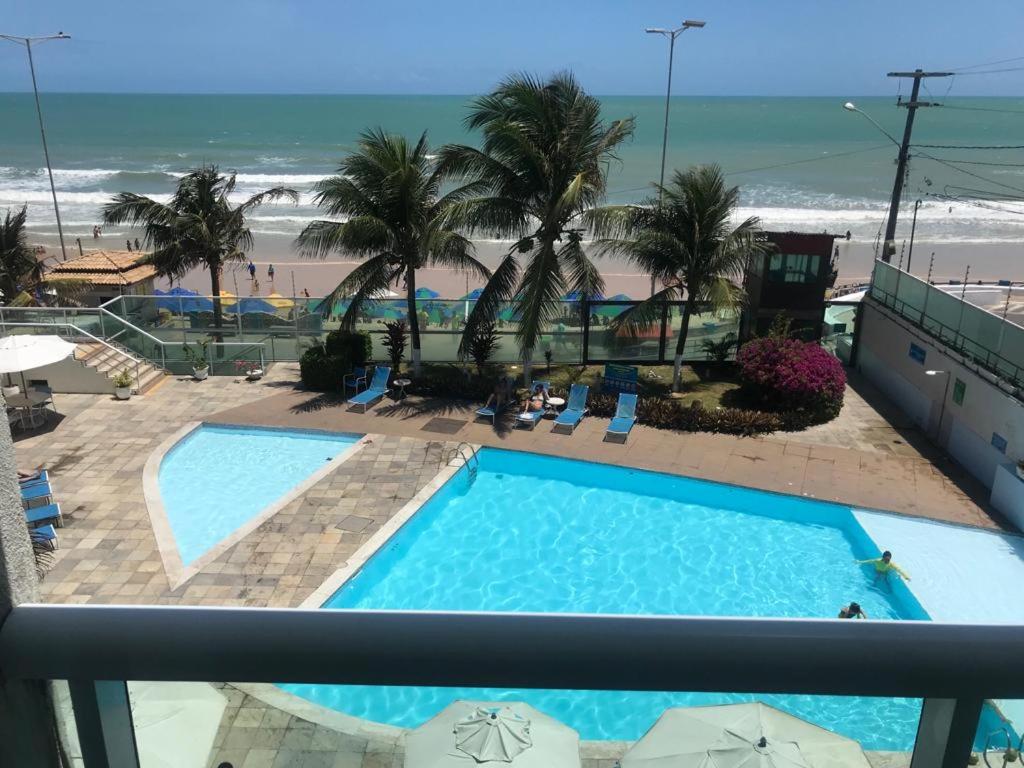 - une vue sur la piscine et la plage depuis le balcon du complexe dans l'établissement Apartamento Ponta Negra, à Natal