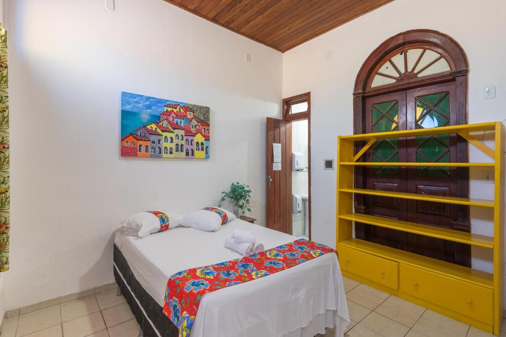 a bedroom with a bed and a yellow cabinet at Pousada Brisa do Mar in Porto Seguro