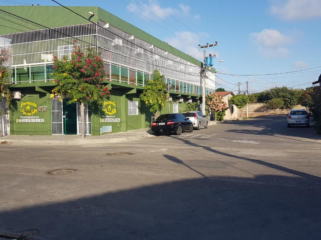 un bâtiment vert avec des voitures garées devant lui dans l'établissement Pousada Pouso Feliz, à Fortaleza