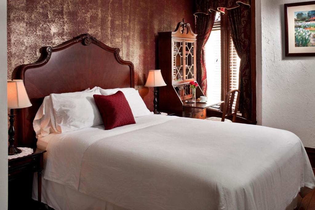 um quarto com uma grande cama branca com almofadas vermelhas em American Guest House em Washington