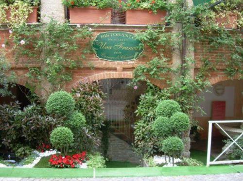 un panneau sur le côté d'un bâtiment avec des plantes dans l'établissement Una Franca Camere Di Charme, à Biella