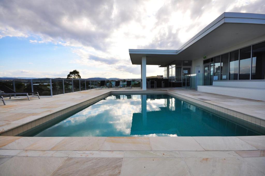 a swimming pool in front of a house at Chancellor Lakeside Apartments in Gold Coast