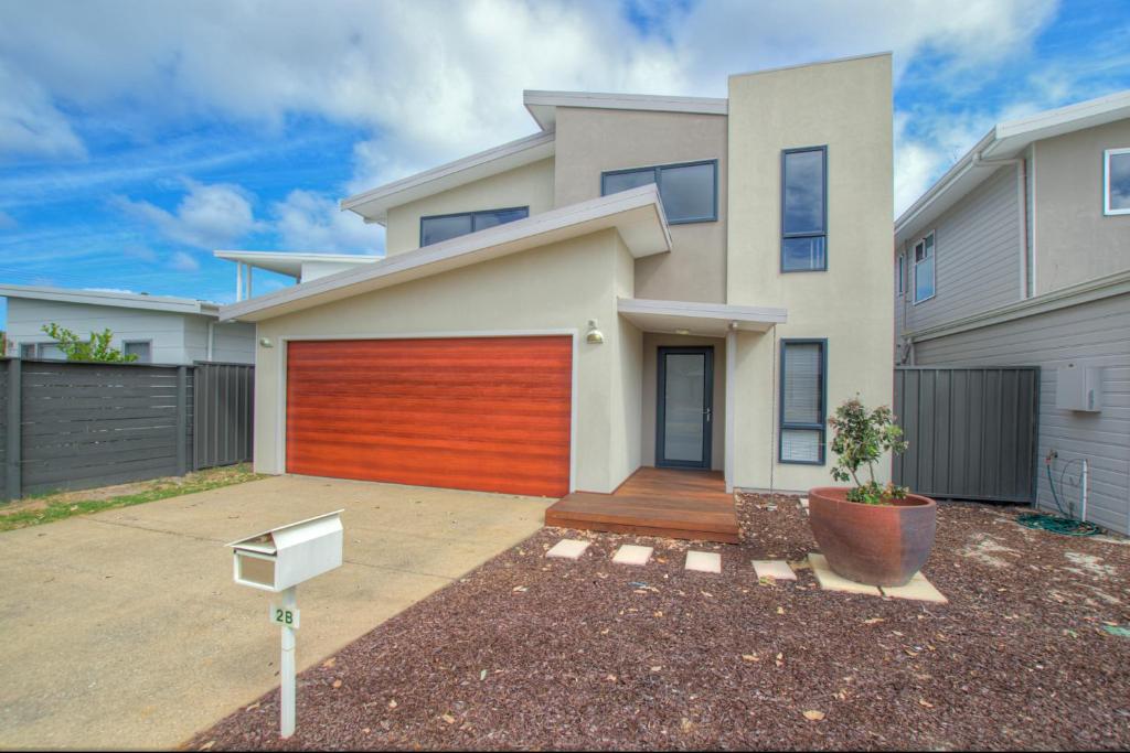 a house with a red garage door in a driveway at A Little Luxury in Town in Dunsborough