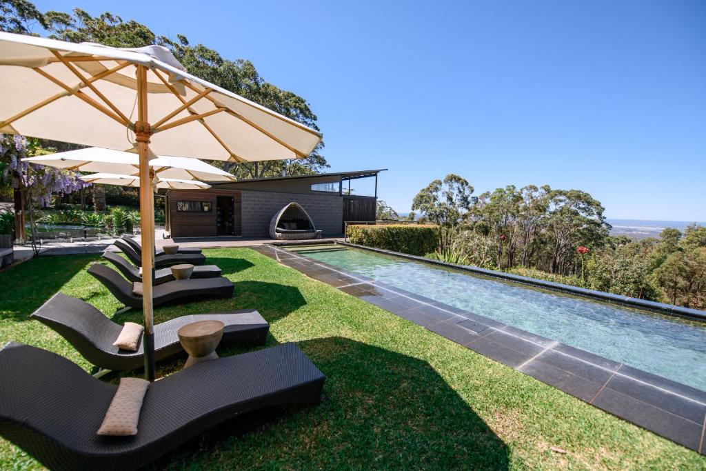 een buitenzwembad met ligstoelen en een parasol bij Spicers Sangoma Retreat - Adults Only in Kurrajong