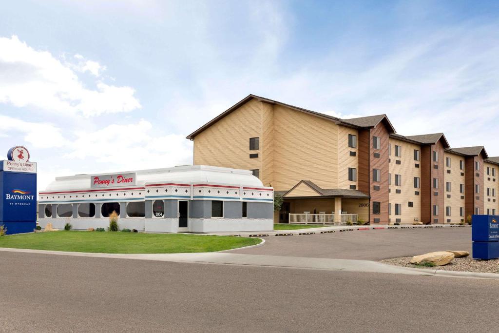 a building with a train in front of a building at Baymont by Wyndham Glendive in Glendive